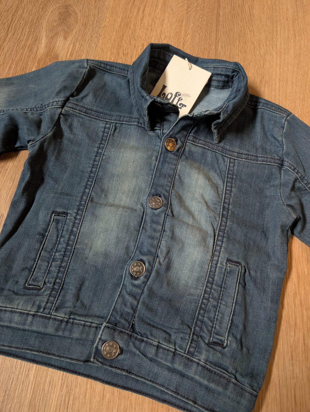 Close-up of the Lofff grey denim jacket showing collar, buttons and tag