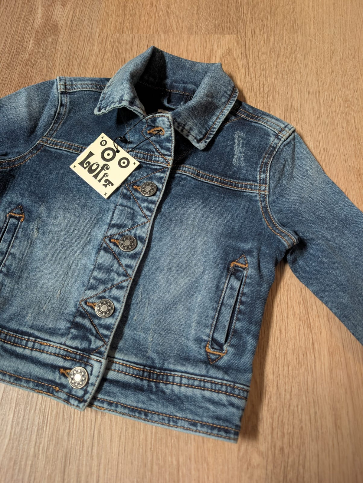 Close-up of the Lofff blue denim jacket showing collar, buttons and tag