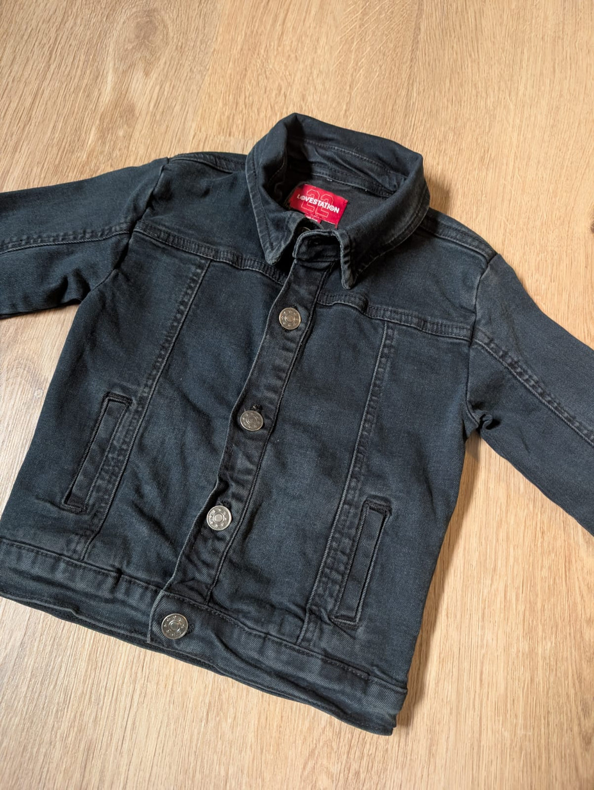 Close-up of the LoveStation22 black denim jacket showing collar and buttons